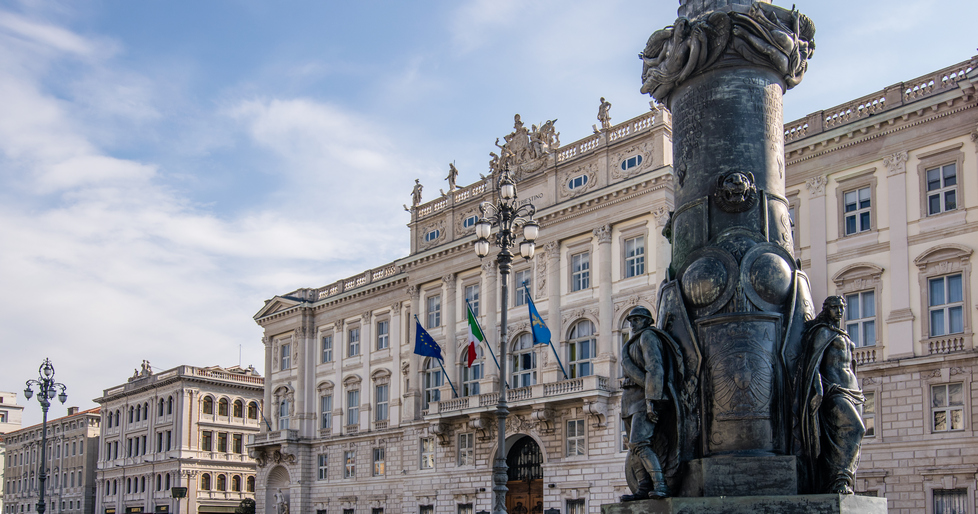 La base dell’imponente portabandiera con sullo sfondo Palazzo Lloyd Triestino, sede della Regione autonoma Friuli Venezia